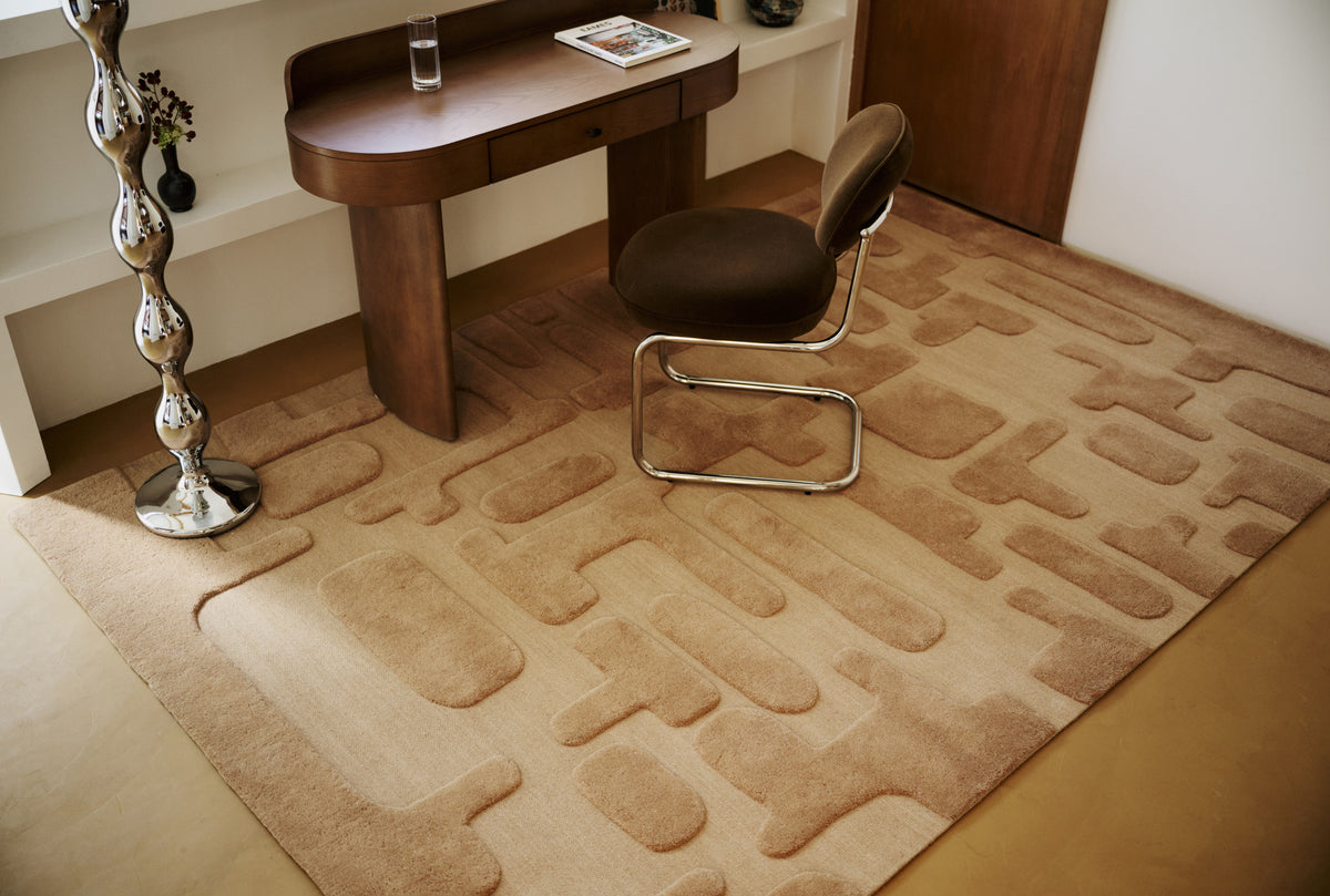 tapis de salon Maze caramel à blocs en relief sous un bureau en bois et sa chaise
