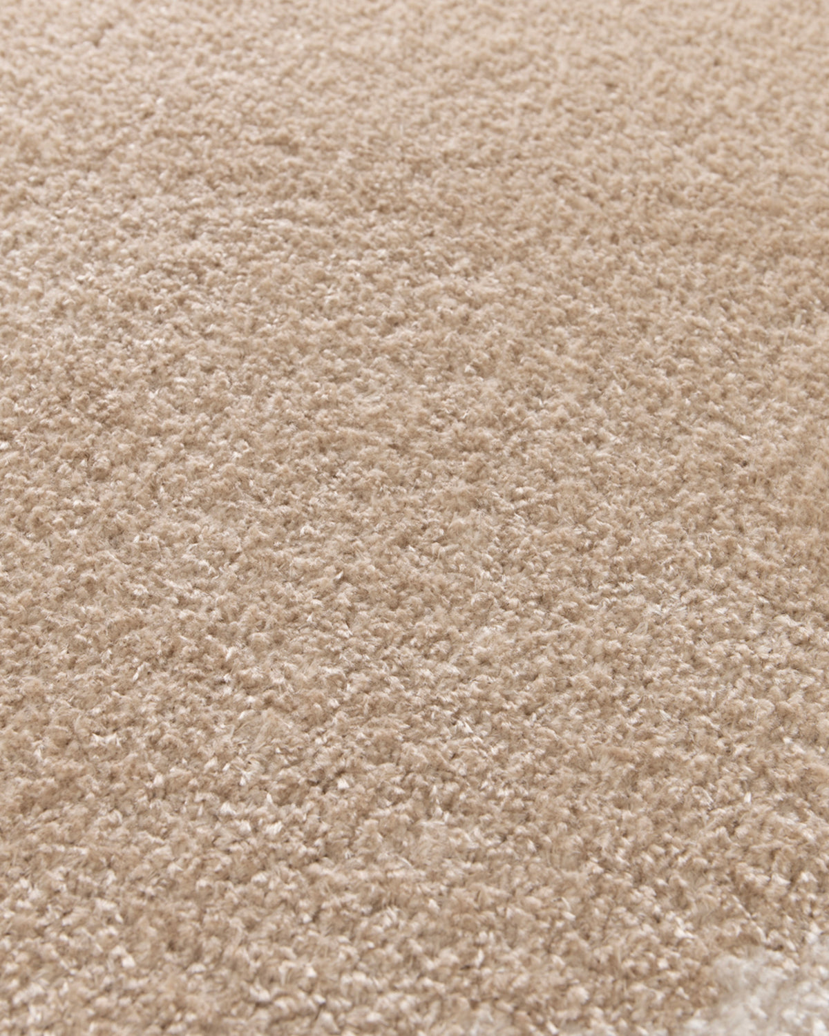 gros plan sur la densité du velours beige et le toucher ras du tapis rond NIMBUS