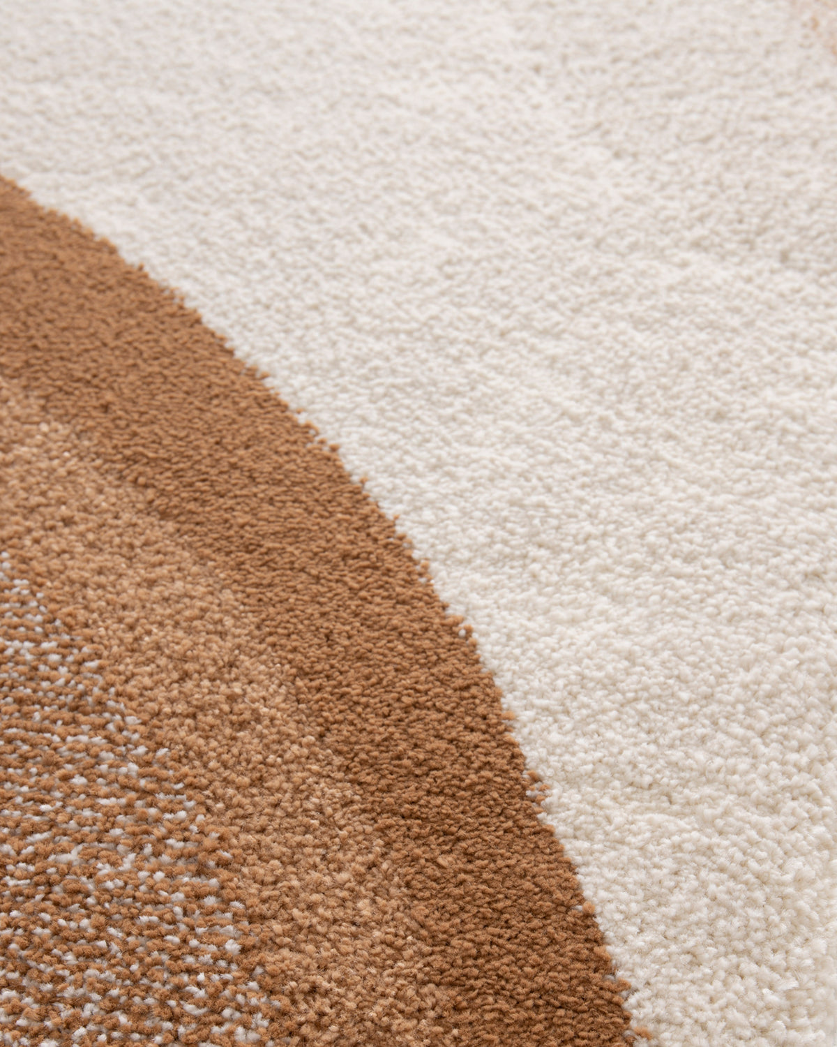 gros plan sur le contraste de textures entre les bandes caramel et écrues d'un tapis Levante