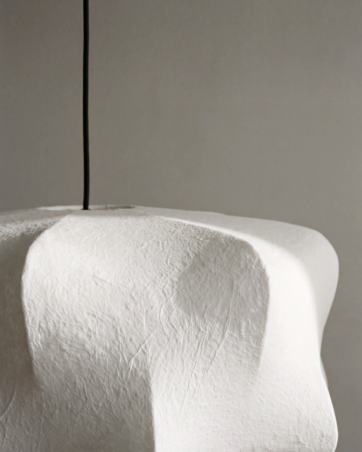 gros plan sur le grain et les plis de la fibre blanche sculptée de la suspension AICHI