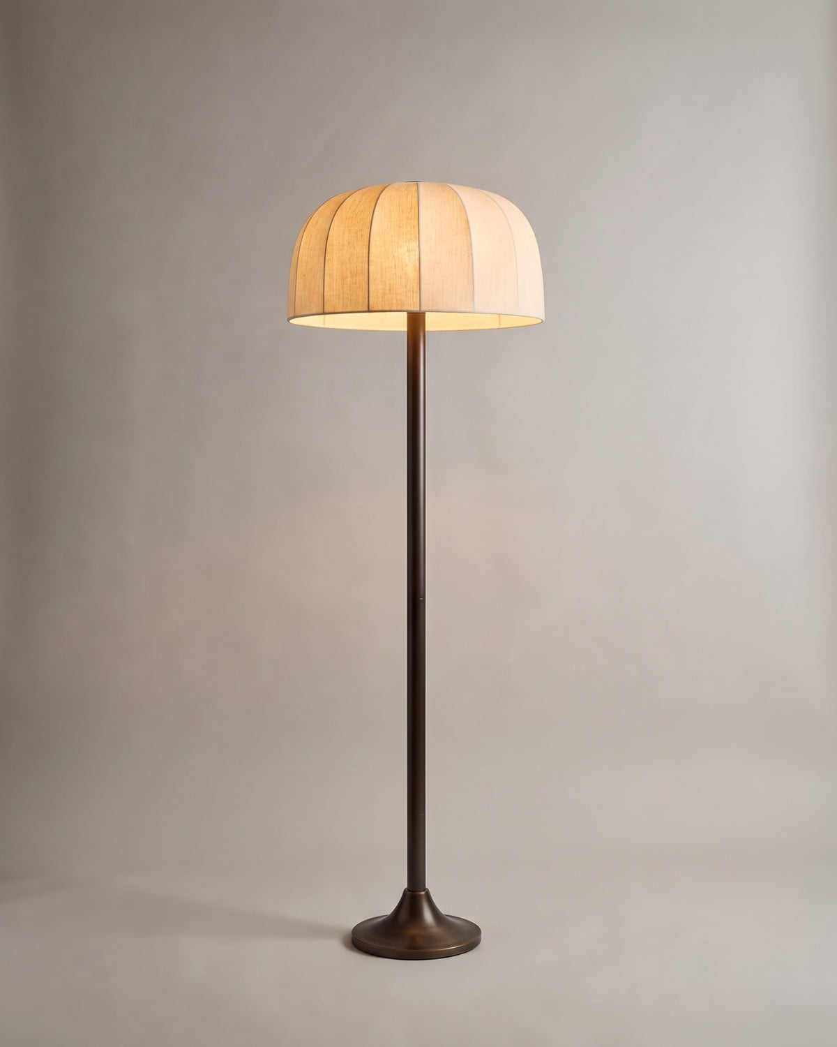 lampadaire BRIGHTON allumé, abat-jour en lin écru à fuseaux et fût en bronze patiné