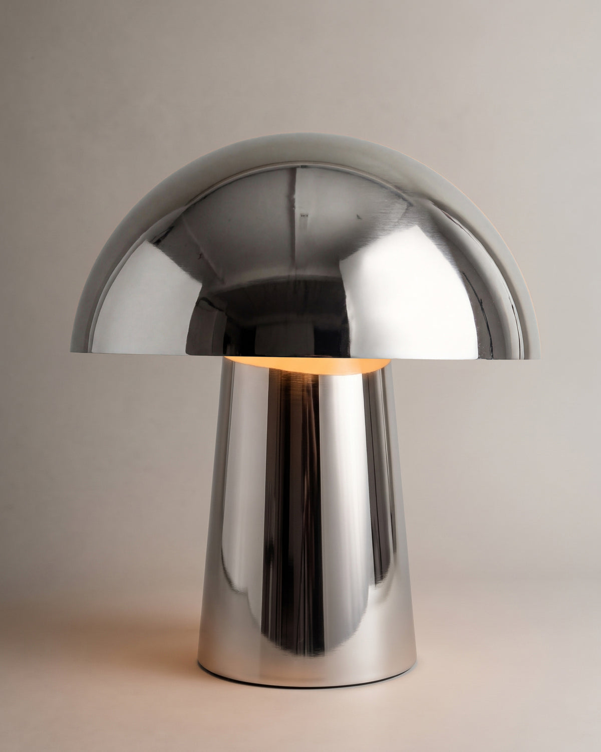 lampe de table CHAMPI allumée, dôme champignon et fût conique en chrome poli miroir