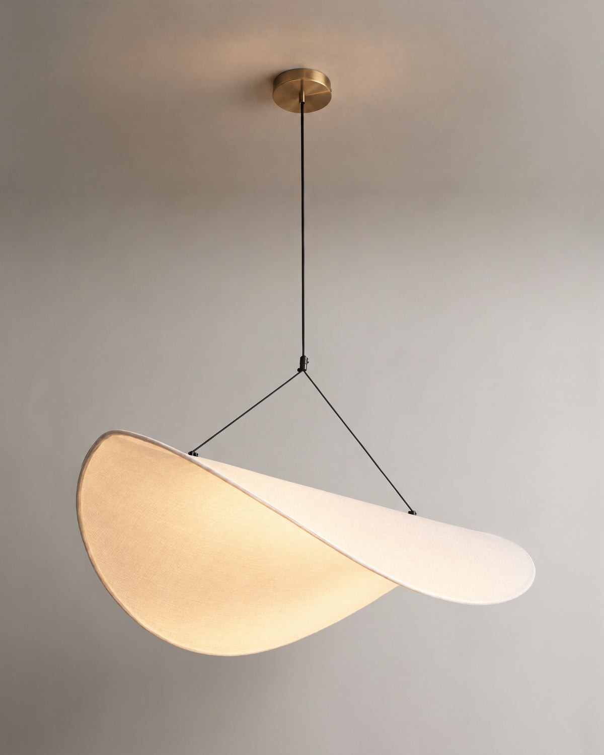 suspension FUKUI allumée, sa toile blanche drapée diffuse une lumière chaude et douce