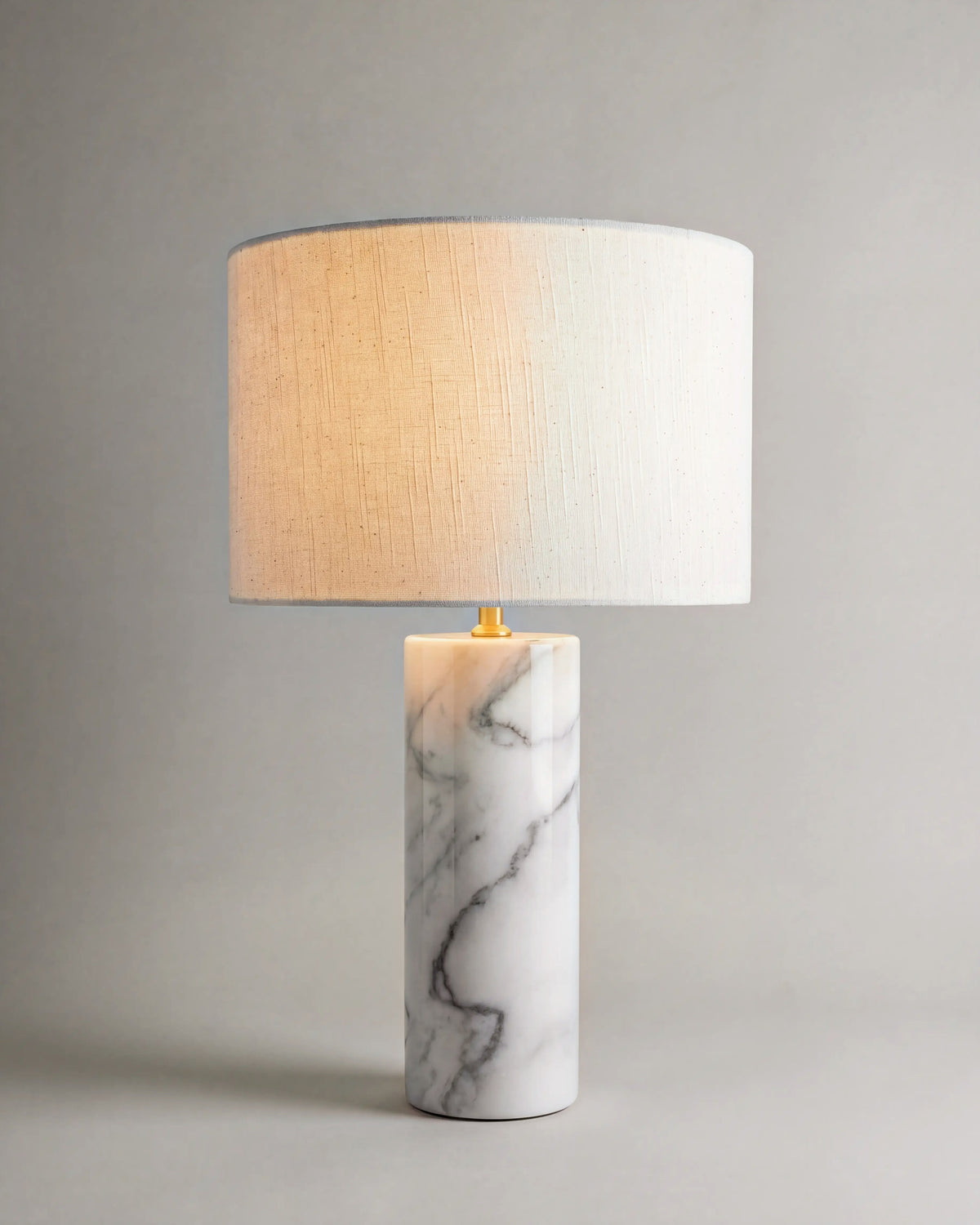 lampe de table GAIA allumée, pied en marbre blanc veiné et abat-jour en lin écru