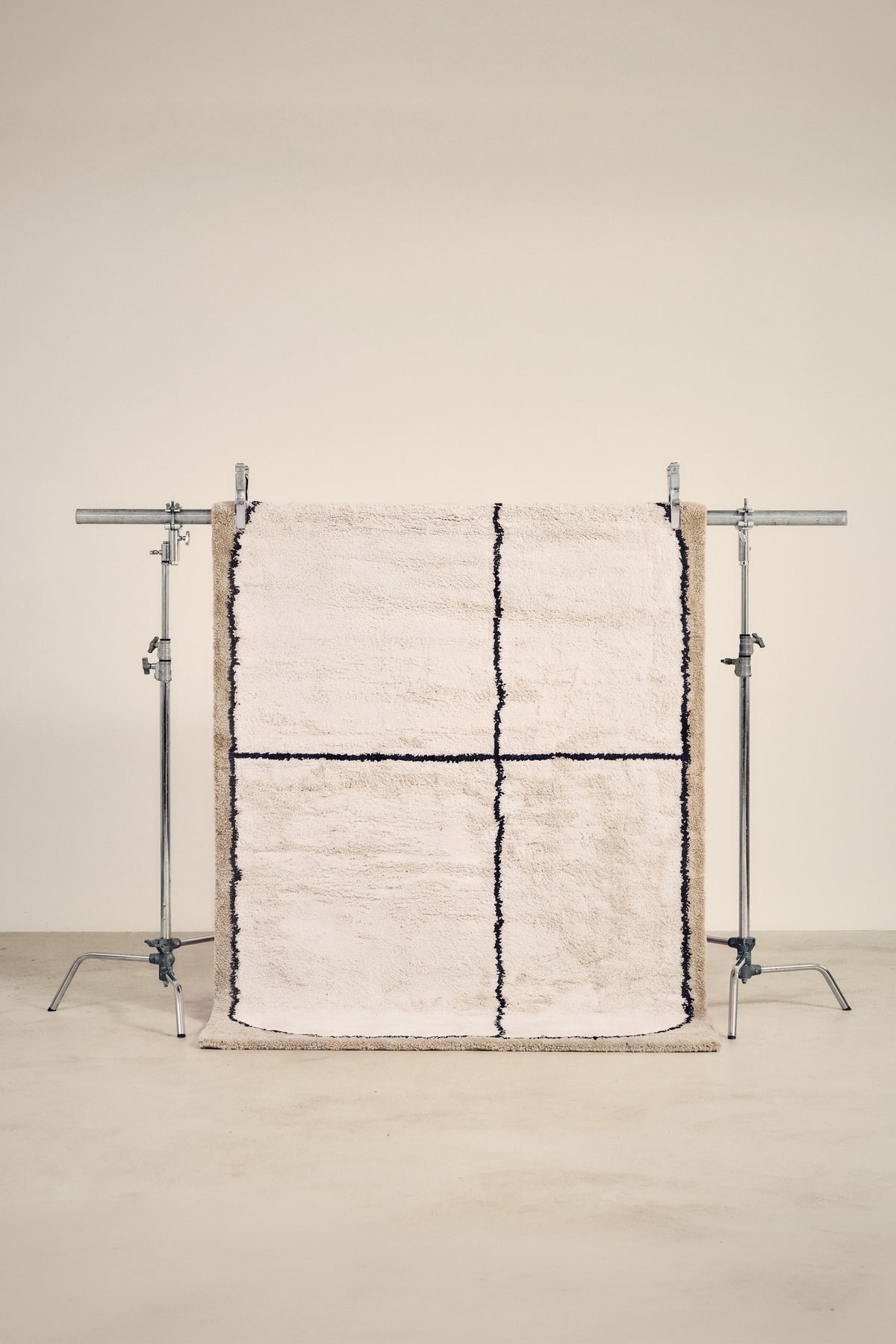 tapis KENTO écru à lignes noires, petit format suspendu sur un portant de studio