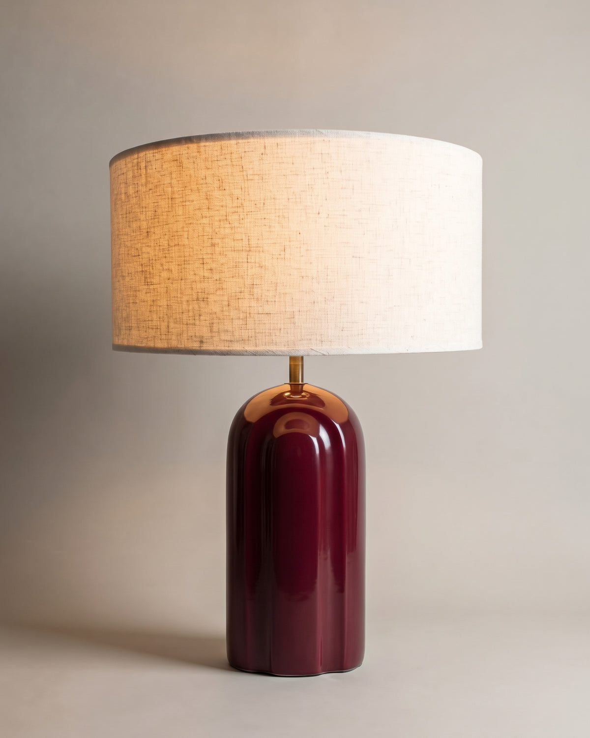 lampe de table LEYANIS allumée, pied en céramique bordeaux brillante et abat-jour écru