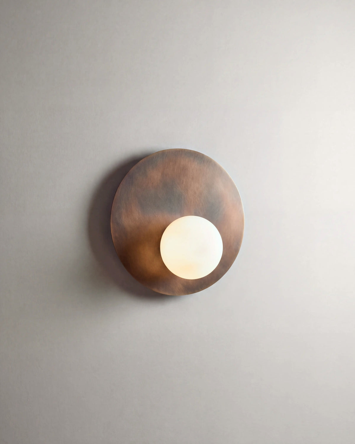 applique murale OLUWA en métal bronze patiné et globe opalin allumée, lumière douce