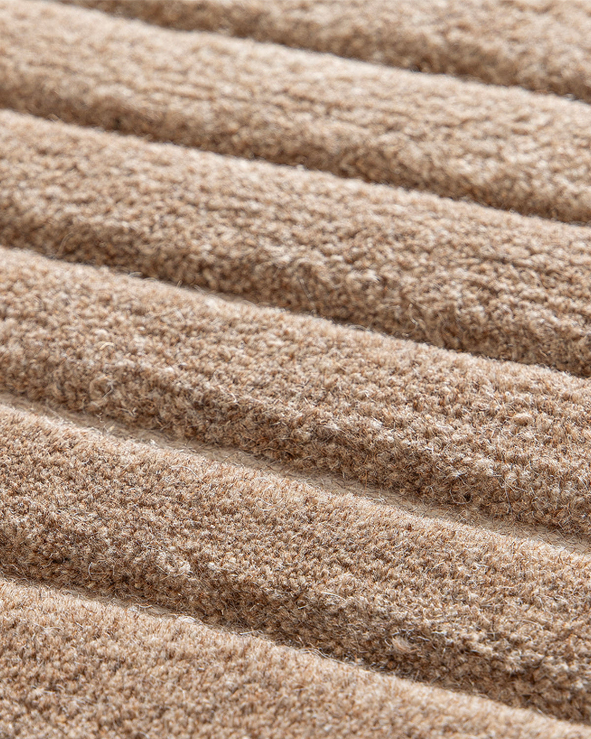gros plan sur les nervures de laine brune en relief qui sculptent le tapis ARCO beige