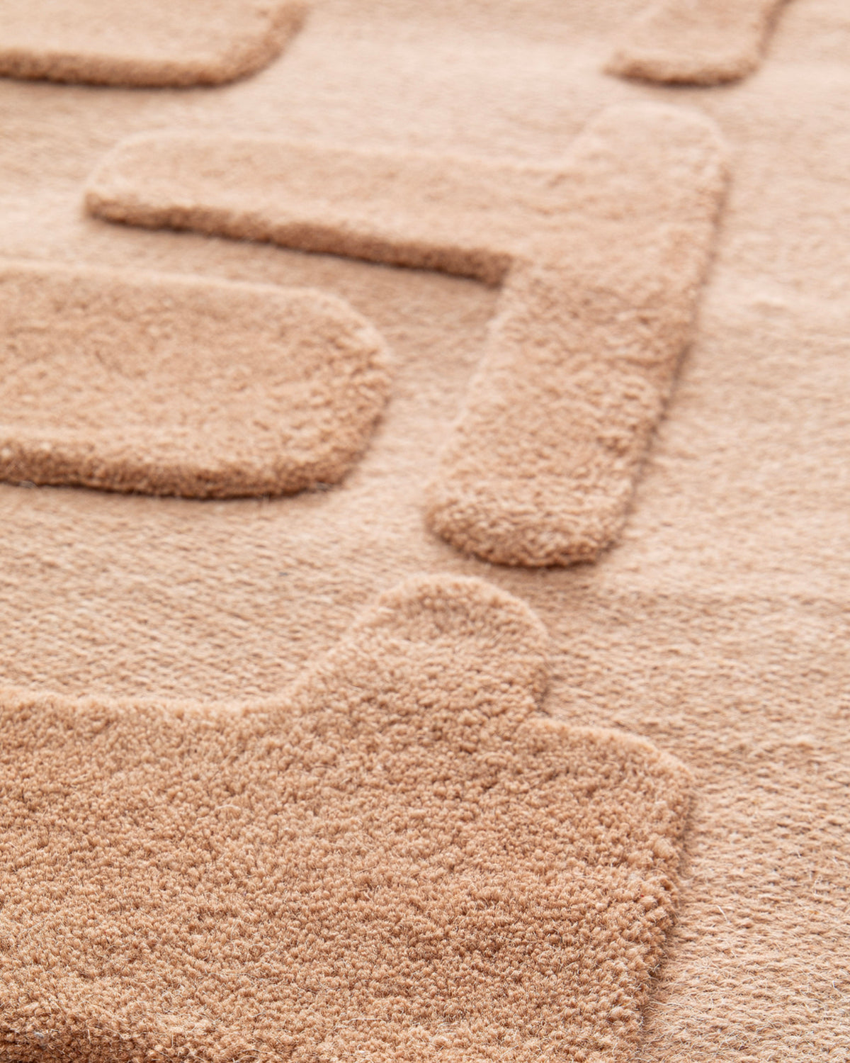 gros plan sur les blocs arrondis en relief du velours caramel d'un tapis de salon Maze