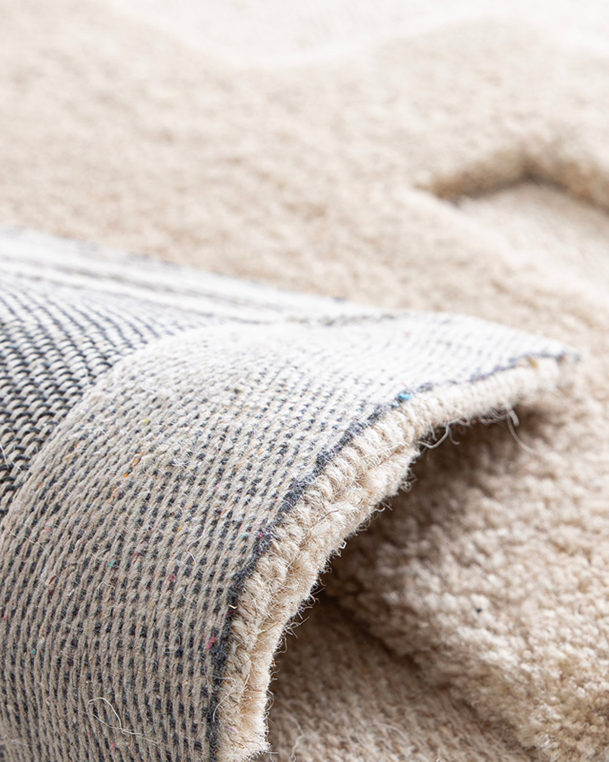gros plan sur l'envers tissé anthracite et la lisière écrue d'un tapis de salon Piazza