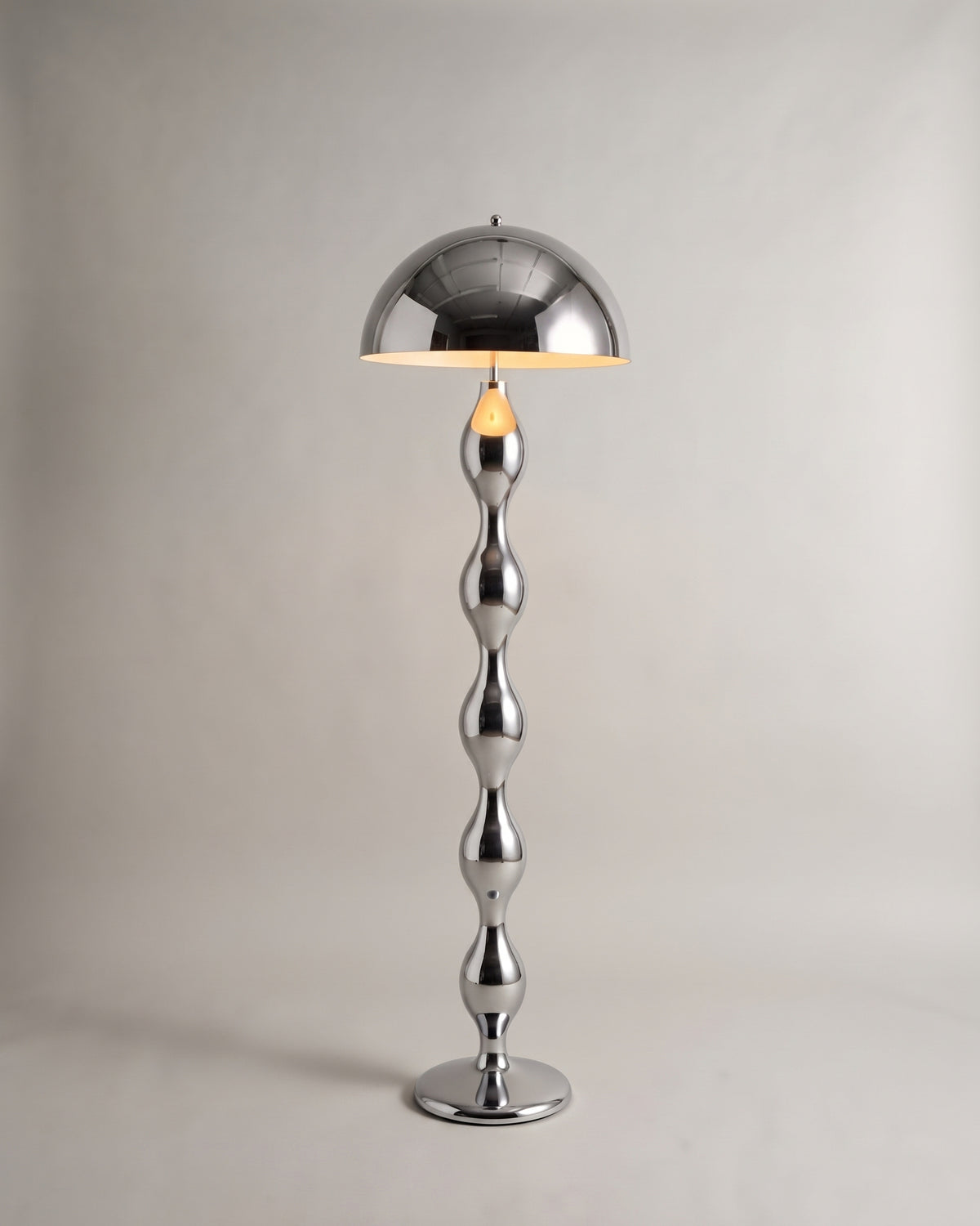lampadaire POWERS chromé allumé, dôme réfléchissant et fût à renflements poli miroir
