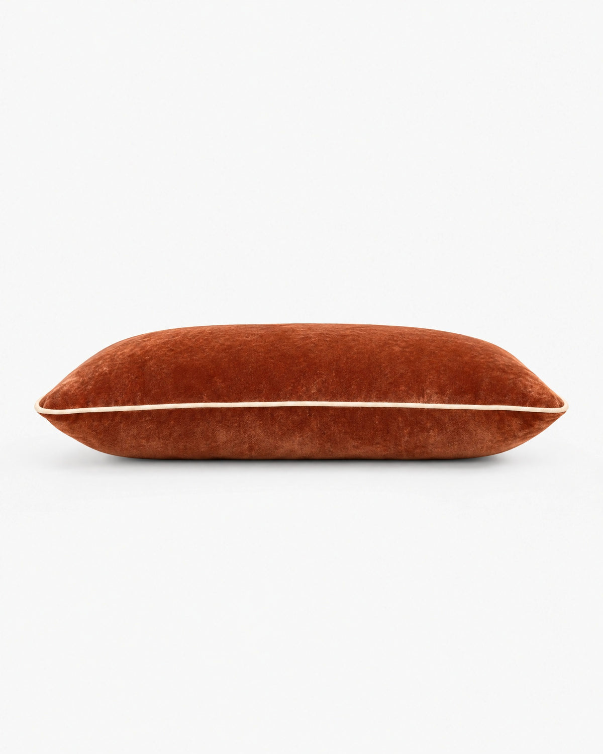 coussin rectangulaire LODGE en velours cognac vu de profil, passepoil écru sur la tranche