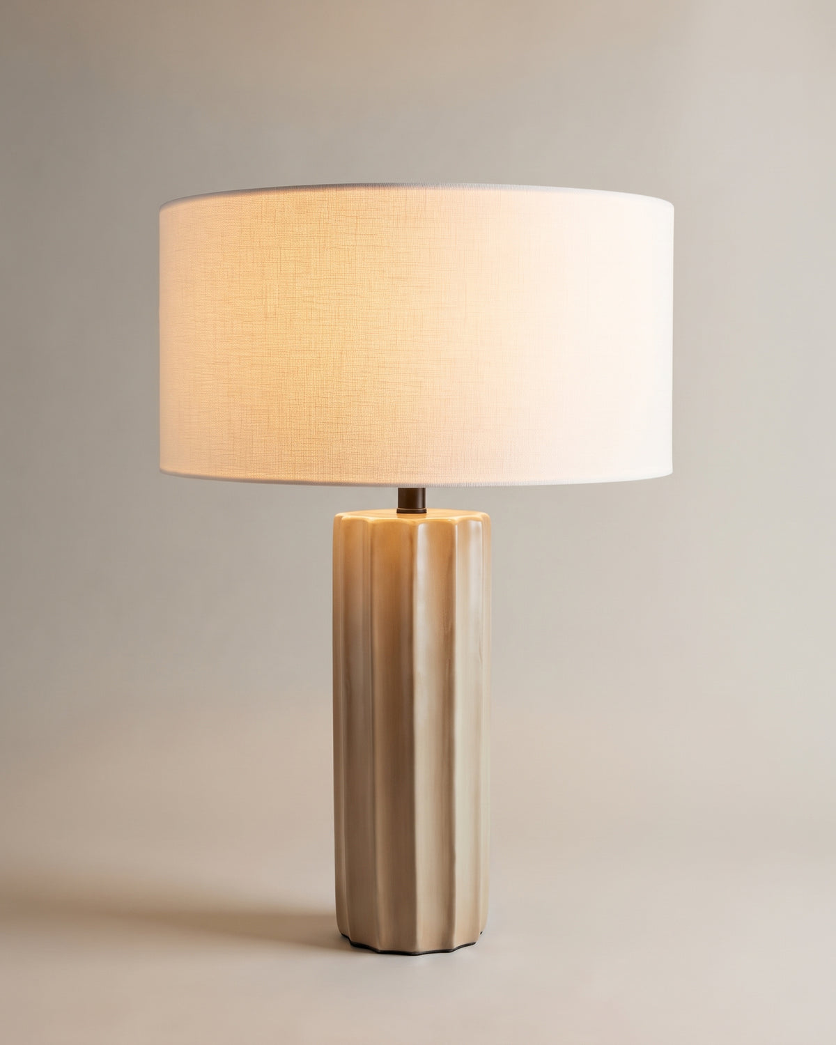 lampe de table ZAHARA allumée, pied cannelé en céramique beige et abat-jour en lin blanc